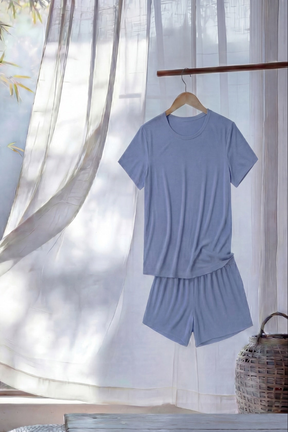 bamboo chambray blue shorts and relaxed tee set from camofleur hanging on a hanger against a light curtain background