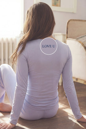 Woman wearing a camofleur lounge set in chambray blue with 'LOVE U' embroidered on the back of the top.