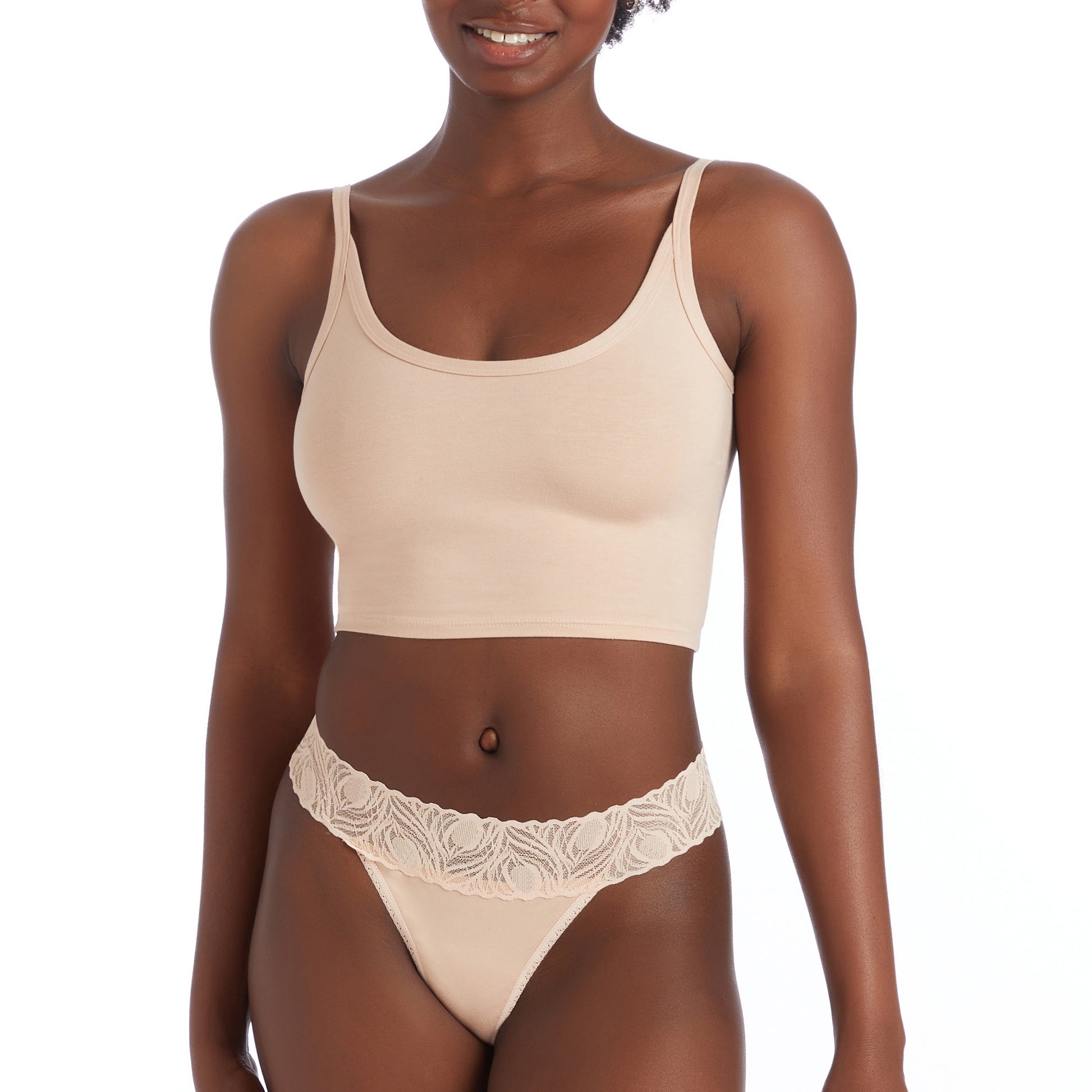 Woman wearing a beige tank top and lace underwear set on a white background