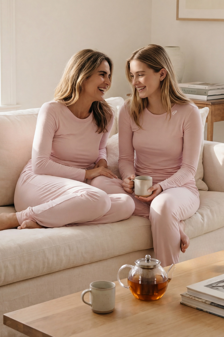 Mother and daughter in matching pink lounge sets from Camofleur sitting on a beige sofa in a bright living room.